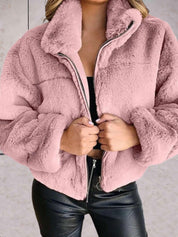 Giacca in pelliccia sintetica rosa, donna, con zip frontale, abbinata a pantaloni in pelle nera. Moda invernale, abbigliamento caldo e trendy.