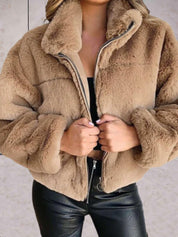 Giacca in pelliccia sintetica beige, donna, con zip aperta, abbinata a pantaloni in pelle nera. Moda autunno inverno, stile casual chic.