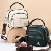 Due borse a tracolla in pelle, una bianca e una verde, con dettagli dorati e cinturini decorati. Design elegante e moderno, perfette per ogni occasione.