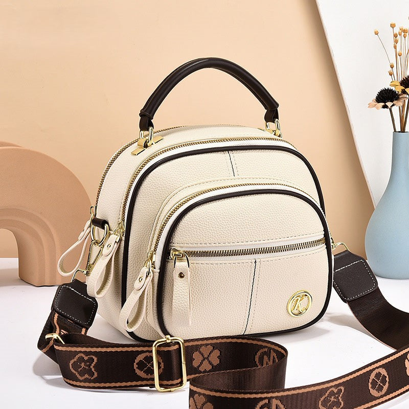 Zaino donna in pelle beige con manico nero, doppia cerniera, tasca frontale, tracolla regolabile marrone, design elegante e moderno.