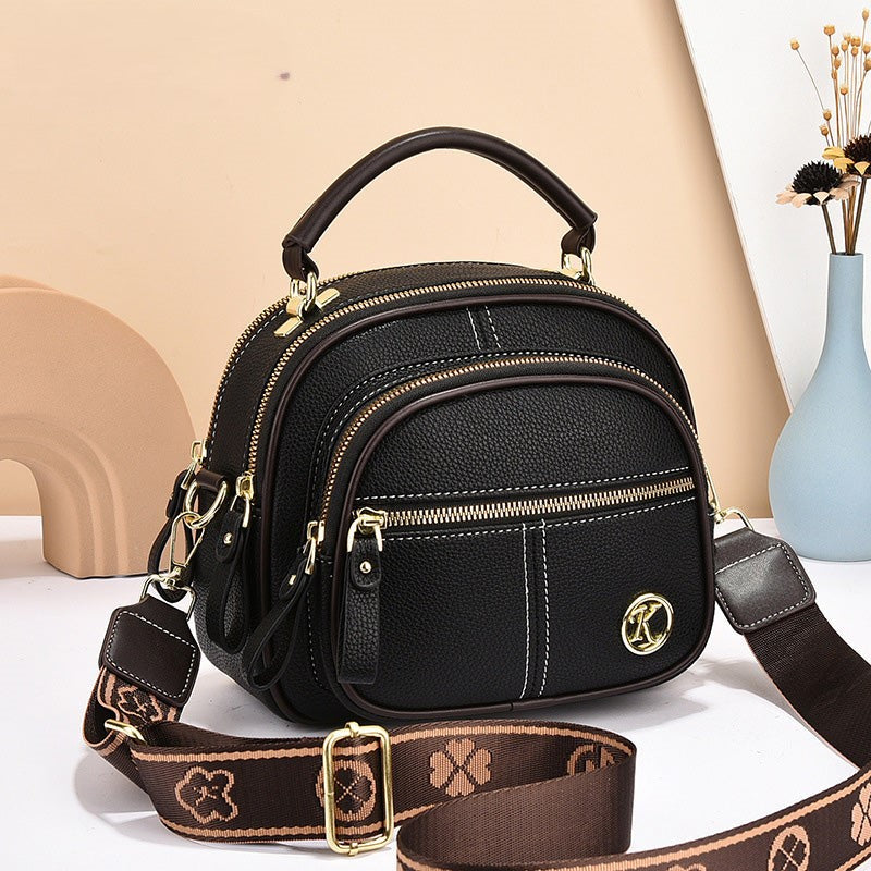 Borsa a tracolla in pelle nera con dettagli dorati, tasche multiple e manico superiore. Design elegante, perfetta per moda donna e accessori.