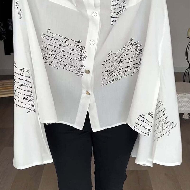 Camicia bianca donna con scritte nere, maniche ampie, bottoni frontali. Moda elegante, tessuto leggero, ideale per look casual e formali.