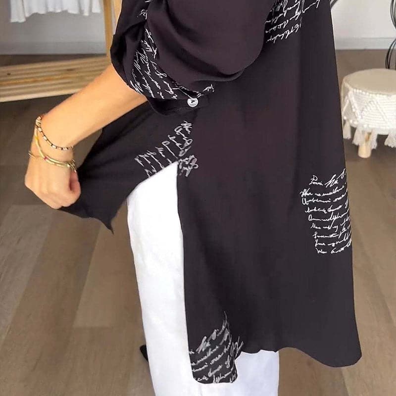 Camicia nera con scritte bianche, maniche lunghe, abbinata a pantaloni bianchi. Moda casual elegante, tessuto leggero, stile moderno.