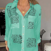Camicia verde donna con scritte nere, colletto classico, maniche lunghe, bottoni frontali. Moda casual elegante, tendenza abbigliamento femminile.