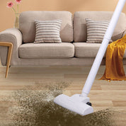 Aspirapolvere senza fili su tappeto sporco in salotto moderno con divano beige e cuscini. Pulizia casa, elettrodomestico efficiente.