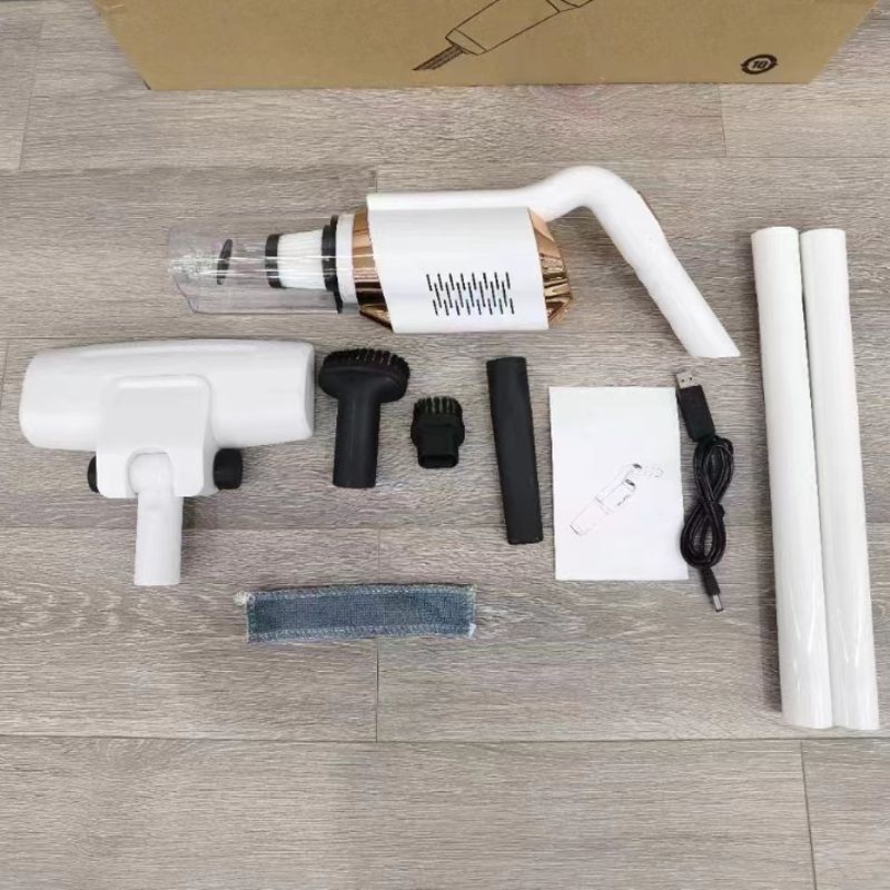 Aspirapolvere portatile senza fili bianco con accessori su pavimento in legno. Include spazzole, tubi di prolunga e cavo USB.