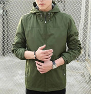 Giacca verde con cappuccio, chiusura a zip, polsini elasticizzati, indossata da uomo. Perfetta per outdoor, moda casual, stile urbano.