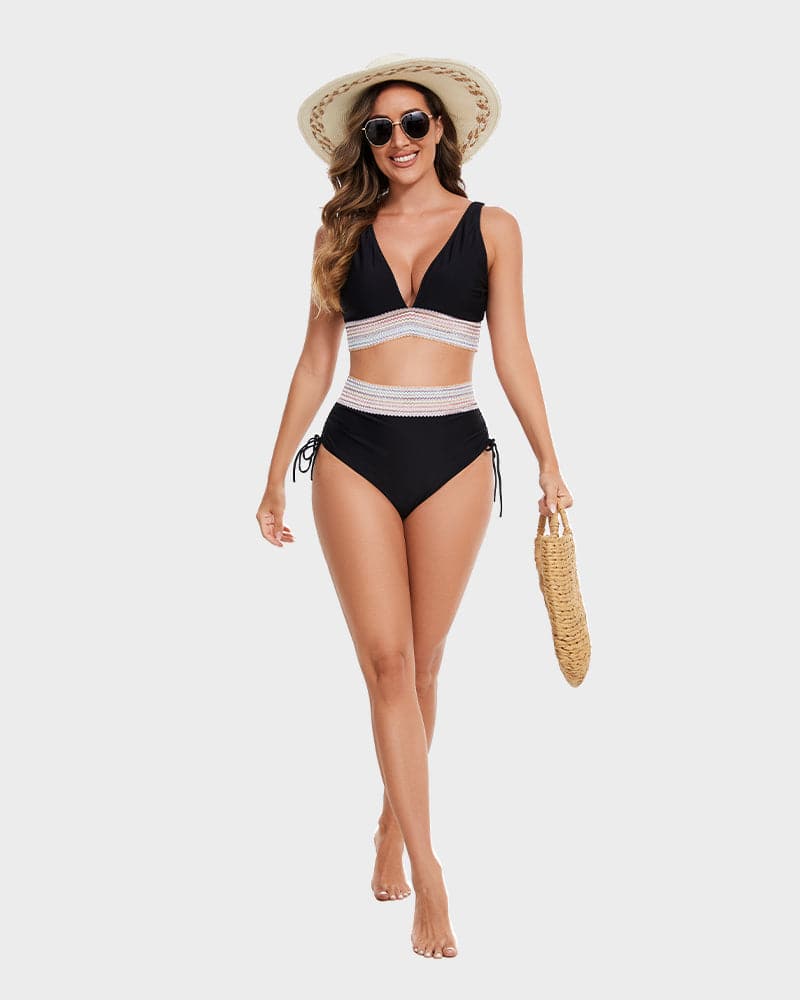 Donna in costume da bagno nero a due pezzi con dettagli bianchi, cappello di paglia, occhiali da sole e borsa intrecciata. Moda estiva mare.