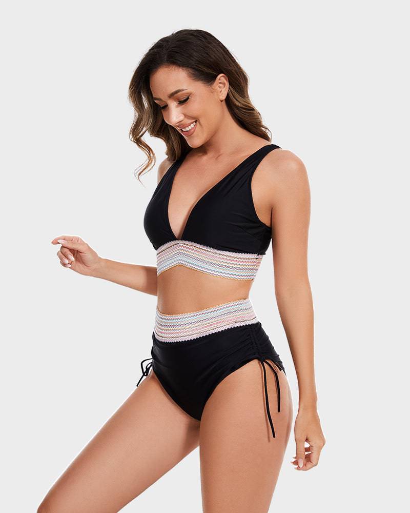 Donna in costume da bagno nero a due pezzi con dettagli a righe colorate, design a vita alta e spalline regolabili. Moda mare estate 2023.