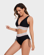 Donna in costume da bagno nero a due pezzi con dettagli a righe colorate, design a vita alta e spalline regolabili. Moda mare estate 2023.