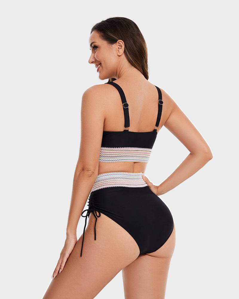 Donna in costume da bagno nero a vita alta con dettagli in pizzo bianco, spalline regolabili, vista posteriore. Moda mare elegante e moderna.