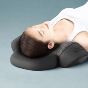 Donna che utilizza un cuscino ergonomico per il collo, nero, su sfondo grigio. Ideale per supporto cervicale e comfort durante il riposo.