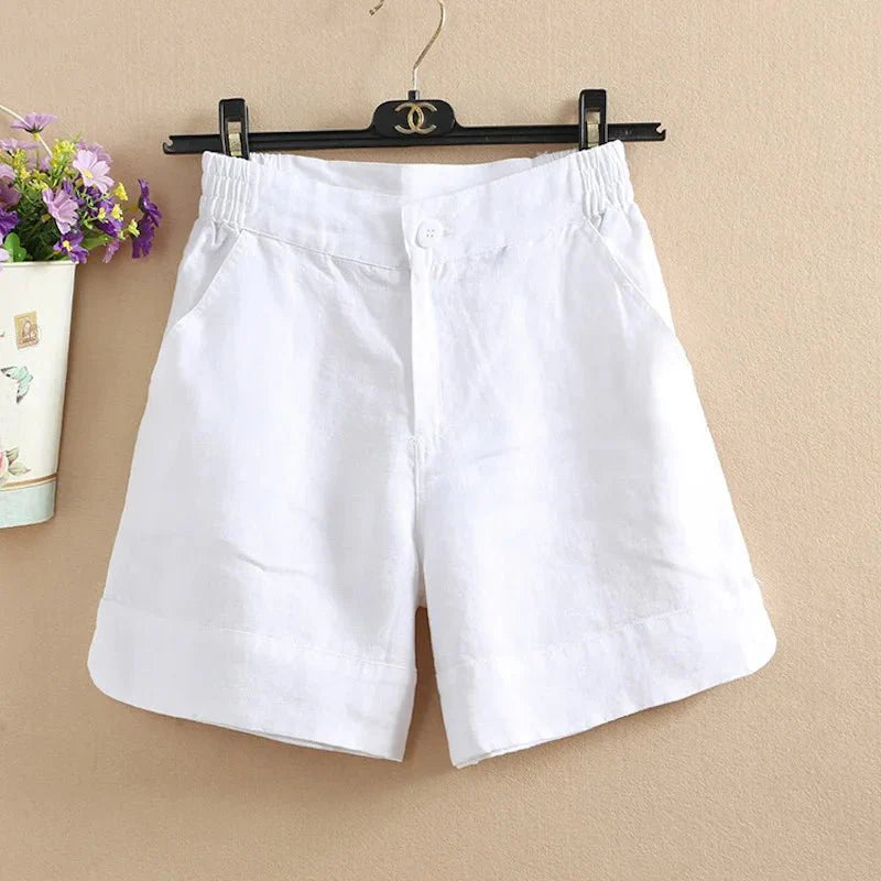 Pantaloncini bianchi in lino per donna, con elastico in vita, appesi su gruccia nera. Ideali per l'estate, comodi e traspiranti.