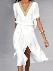 Abito bianco elegante con scollo a V decorato, maniche corte e gonna a portafoglio. Perfetto per eventi estivi e cerimonie. Moda donna chic.