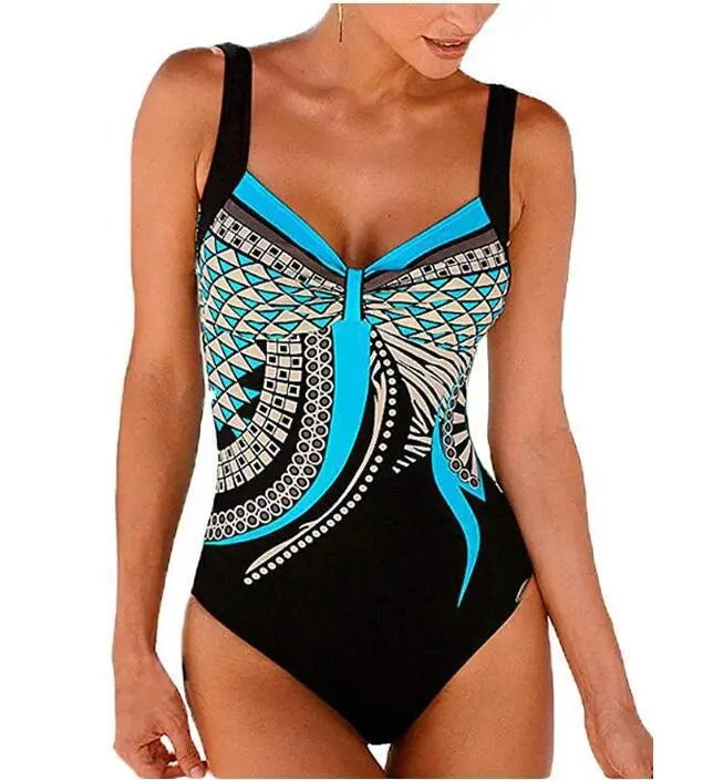 Costume intero donna nero con motivo geometrico blu e bianco, spalline larghe, scollo a V. Elegante e moderno, perfetto per la spiaggia o piscina.