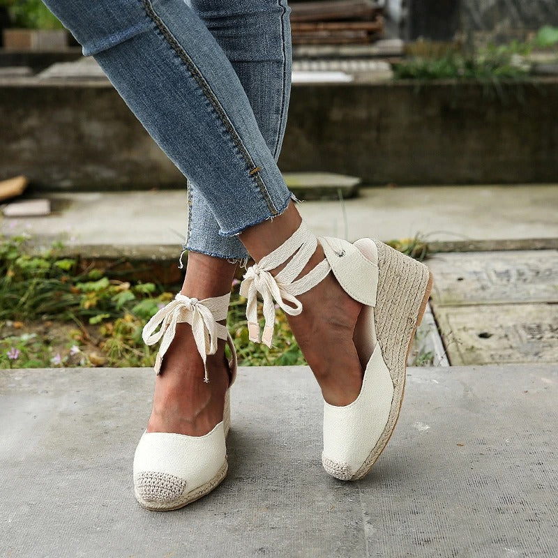 Scarpe espadrillas donna con zeppa in corda, colore bianco, lacci alla caviglia, abbinate a jeans aderenti. Stile casual estivo, moda femminile.