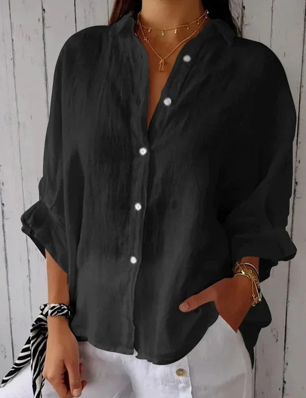 Camicia nera da donna in lino, maniche lunghe, bottoni bianchi, stile casual elegante, abbinata a pantaloni bianchi.
