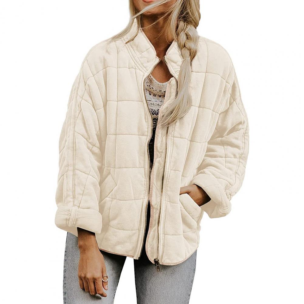 Giacca trapuntata beige da donna, stile casual, con zip frontale e maniche lunghe, indossata su jeans. Moda autunnale, abbigliamento femminile trendy.