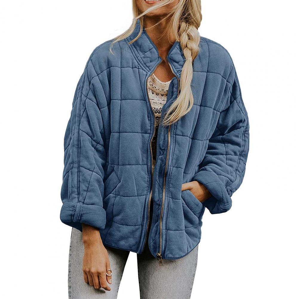 Giacca trapuntata blu donna, stile casual, con zip frontale e tasche, indossata su maglia chiara e jeans. Moda autunnale, abbigliamento femminile.