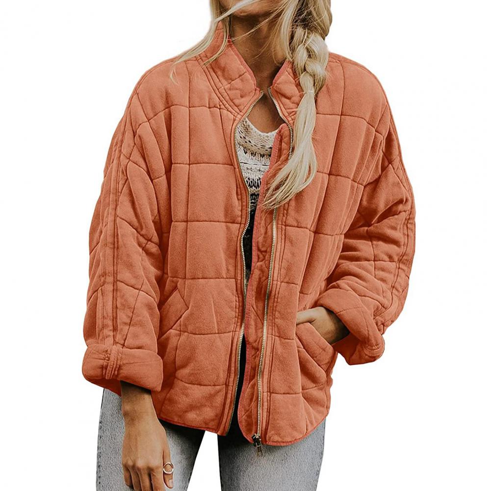 Giacca trapuntata arancione da donna, stile casual, con zip frontale e tasche, indossata su maglia bianca. Moda autunnale, abbigliamento femminile trendy.
