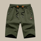 Pantaloncini cargo verde oliva da uomo con coulisse, tasche laterali con zip, dettagli tricolore. Ideali per attività all'aperto e casual.