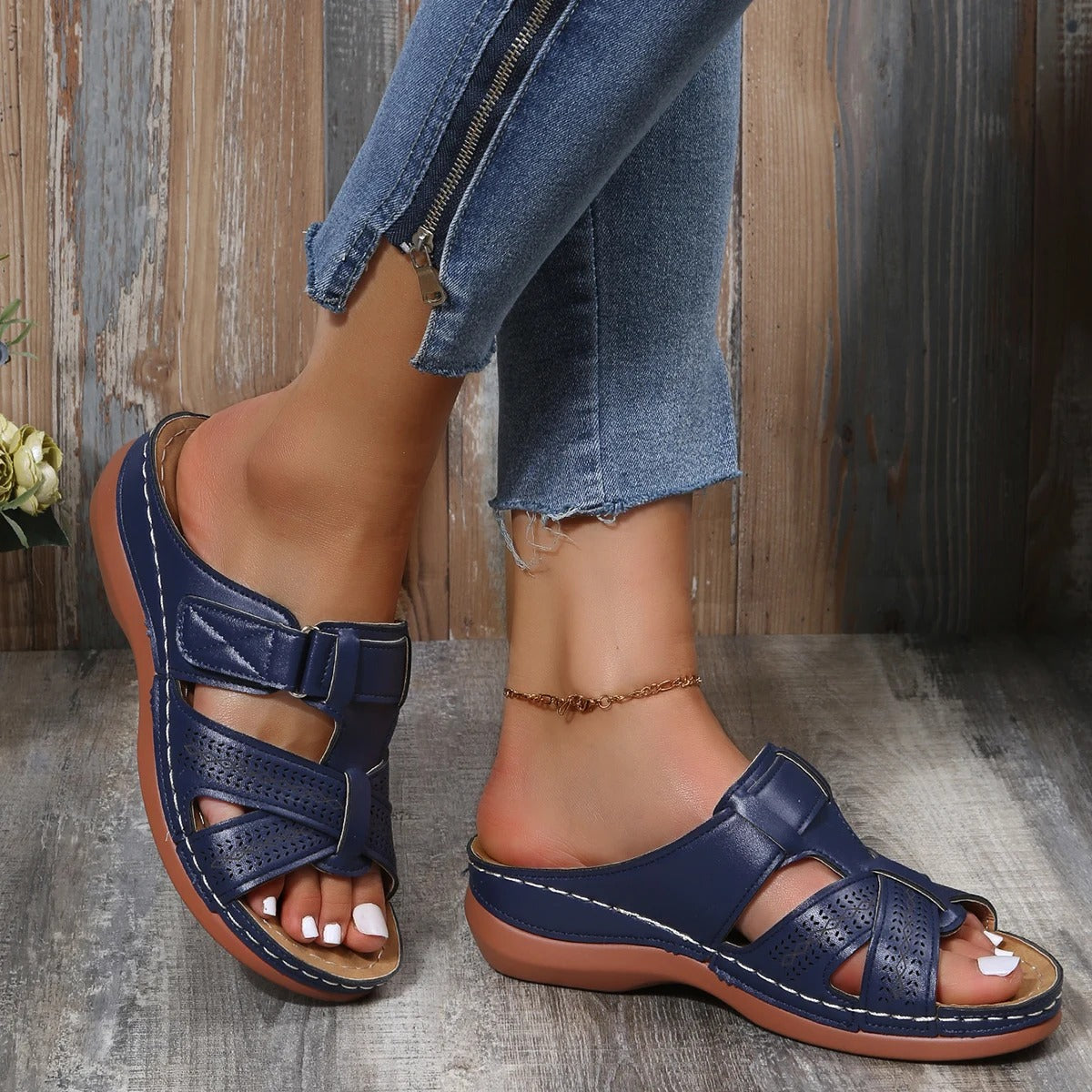 Sandali donna blu con doppia fibbia, suola in gomma marrone, indossati con jeans aderenti. Calzature estive comode e alla moda.