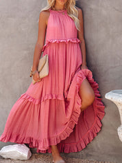 Abito lungo estivo rosa con balze, senza maniche, indossato da donna. Perfetto per moda estiva, look casual elegante. Accessoriato con borsa beige.