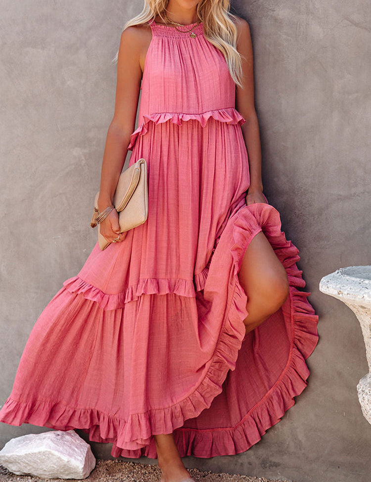 Abito lungo estivo rosa con balze, senza maniche, indossato da donna. Perfetto per moda estiva, look casual elegante. Accessoriato con borsa beige.