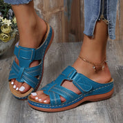 Sandali donna blu in pelle traforata, con suola in gomma e chiusura a strappo, indossati con jeans. Calzature estive comode e alla moda.