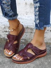 Sandali donna in pelle marrone con cinturino, indossati con jeans strappati. Calzature estive comode, moda casual, tendenza 2023.