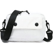 Borsa a tracolla bianca in tessuto a coste, con patta frontale e bottoni neri, tracolla regolabile nera. Accessorio moda casual e versatile.