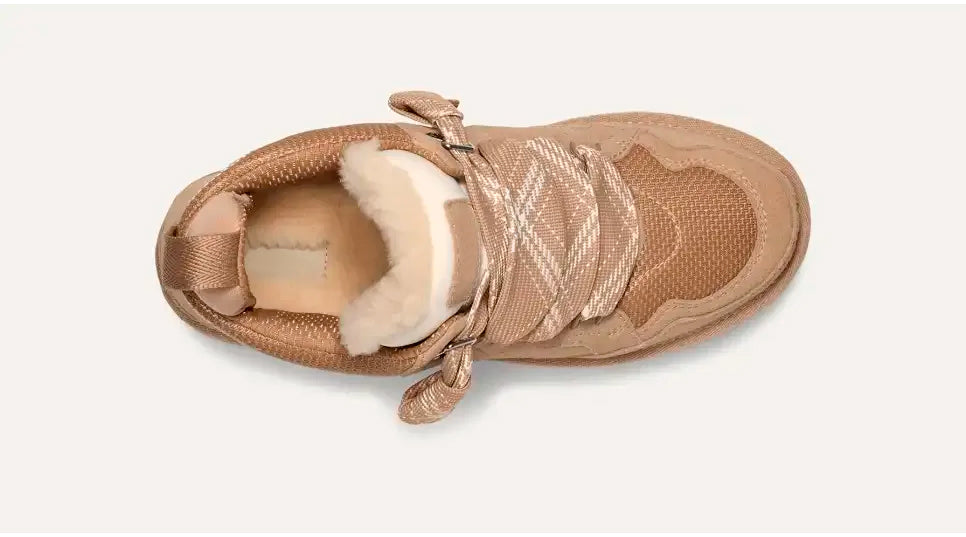 Scarpa da ginnastica beige con lacci incrociati, interno in pelliccia sintetica, vista dall'alto. Design moderno e confortevole per moda casual.