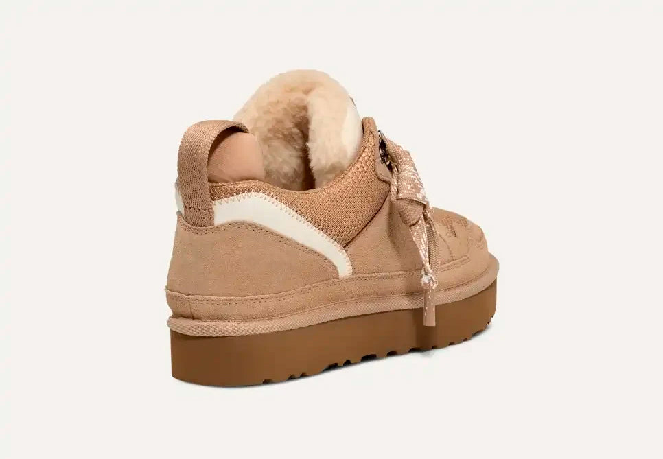 Scarpa invernale beige da donna con suola in gomma, dettagli in pelliccia sintetica e lacci decorativi. Design casual e confortevole.