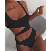 Donna in costume da bagno nero intero con cut-out, collana dorata, unghie bianche. Moda mare, abbigliamento estivo, tendenze beachwear.