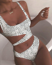 Costume da bagno intero donna bianco con stampa maculata nera, design cut-out, indossato da modella. Moda mare estiva, tendenze beachwear.