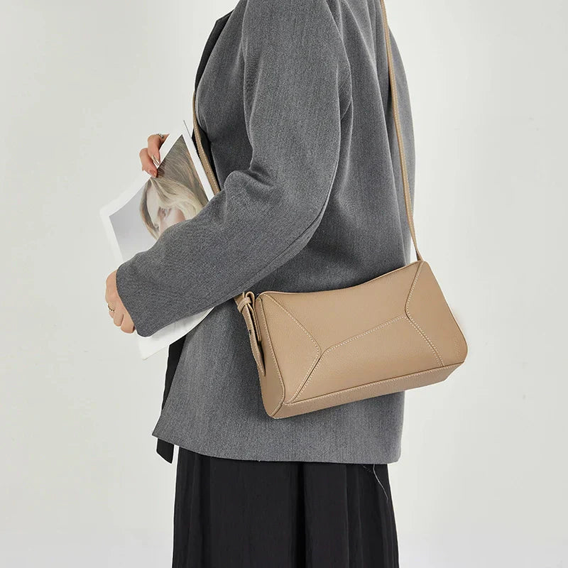 Borsa a tracolla beige in pelle, design elegante e minimalista, indossata su cappotto grigio. Accessorio moda donna, stile casual chic.