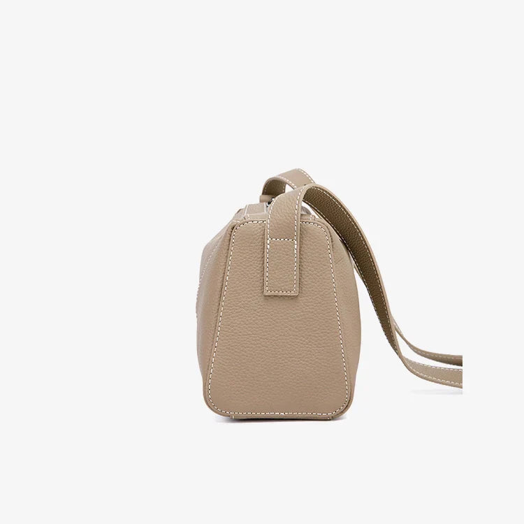 Borsa a tracolla beige in pelle, vista laterale, design elegante e minimalista, cuciture bianche, accessorio moda donna, stile casual chic.