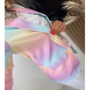 Giacca multicolore pastello sfumata, dettagliata con colori arcobaleno, indossata da una persona con unghie rosa. Moda primavera estate.