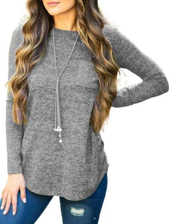 Maglia grigia a maniche lunghe da donna, abbinata a jeans strappati blu e collana lunga. Look casual e moderno per l'autunno.