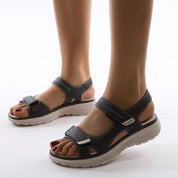 Sandali donna neri con cinturino in velcro, suola ergonomica beige, design casual estivo, comfort e stile per passeggiate e tempo libero.