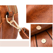 Borsa in pelle marrone con dettagli in metallo dorato, chiusura a zip e bottoni a pressione. Design elegante e resistente, ideale per moda e accessori.