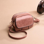 Borsa a tracolla in pelle marrone con doppia cerniera, design elegante e compatto, ideale per moda donna. Accessorio versatile e di tendenza.