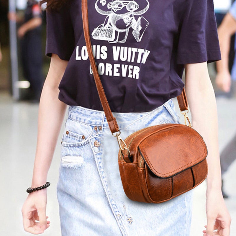 Borsa a tracolla in pelle marrone su donna con maglietta grafica e gonna di jeans. Accessorio moda elegante, perfetto per look casual e chic.