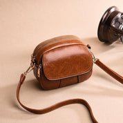 Borsa a tracolla in pelle marrone, design compatto con cerniera dorata, ideale per moda donna. Accessorio elegante e versatile.