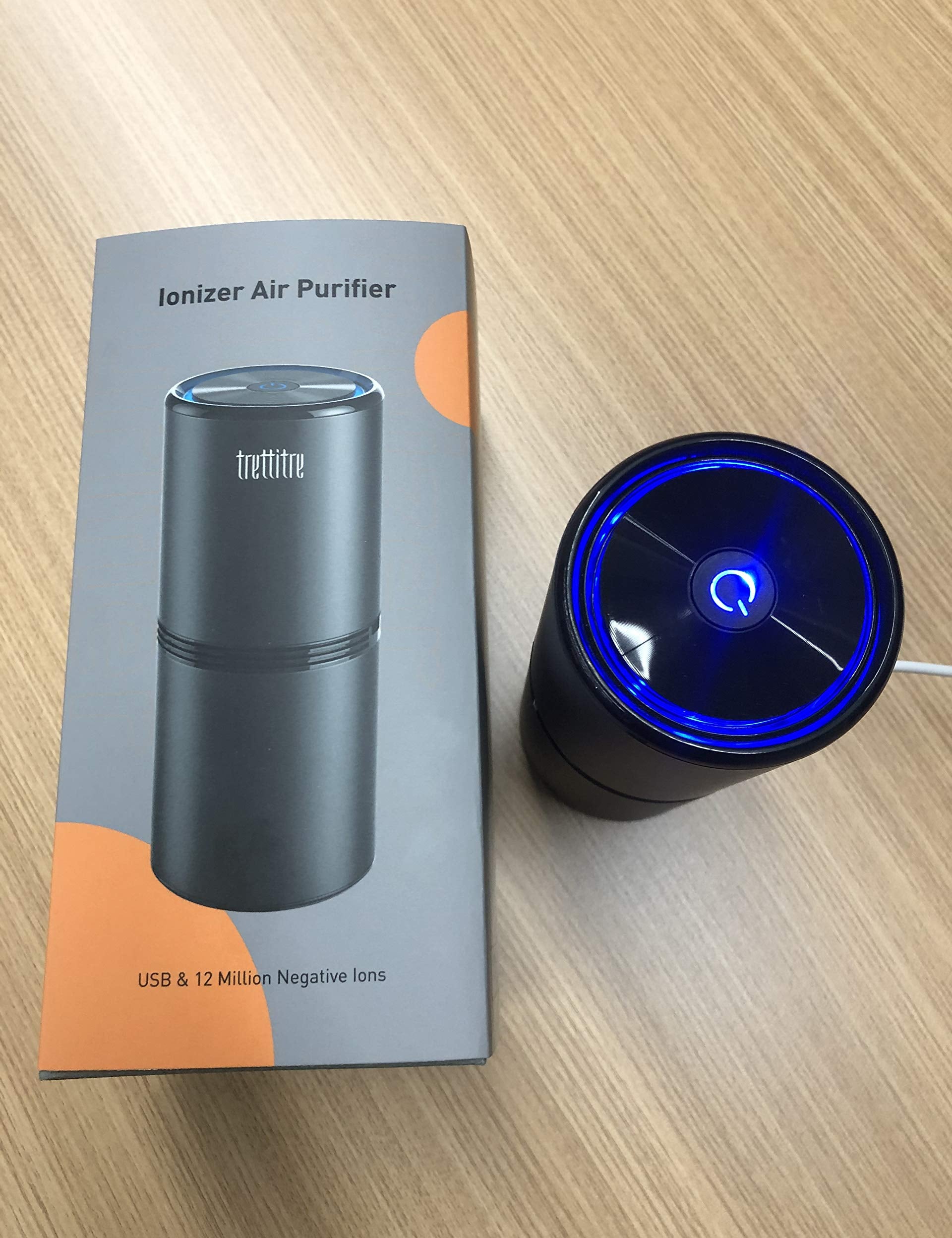 Purificatore d'aria ionizzatore nero su tavolo in legno, con confezione. USB, 12 milioni di ioni negativi. Design compatto, luce LED blu.